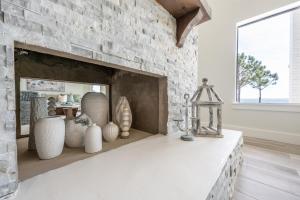 a living room with a stone fireplace with vases at Sea La Vi in Navarre