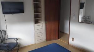 a room with a tv and a chair and a mirror at Casa charmosa com vista e lazer in Belo Horizonte +23 photos