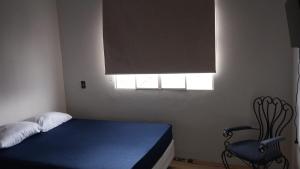 a bedroom with a bed and a chair and a window at Casa charmosa com vista e lazer in Belo Horizonte