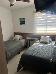 a bedroom with two beds and a ceiling fan at Depto Moderno Oceanna frente a playa cerritos in Mazatlán +15 photos