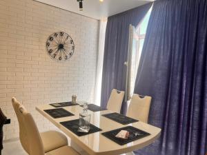 a dining room table with chairs and a clock on the wall at Golden Bugas Sea View Золотий бугаз in Karolino-Buhaz