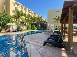 a pool at a hotel with chairs and tables at Depto Moderno Oceanna frente a playa cerritos in Mazatlán