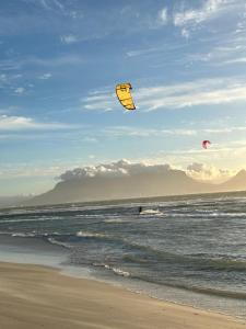 Due persone volano aquiloni sulla spiaggia di OCEAN BREEZE SUNSET BEACH - Cape Town a Città del Capo