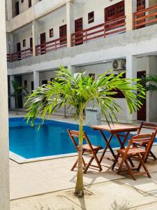 a palm tree next to a table and chairs next to a pool at Flat 02 Residencial ibiapaba in Camocim
