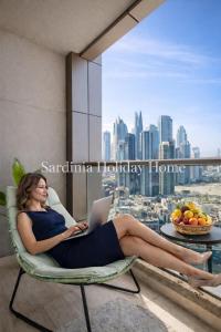 a woman sitting in a chair with a laptop at Studio for 4 just 5 Min Walk to Burj Khalifa, Downtown Dubai, Tower Elite 1 in Dubai