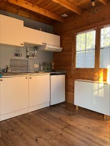 a kitchen with white cabinets and a wooden ceiling at Chalet en lisiere de Foret in Lacanau +6 photos