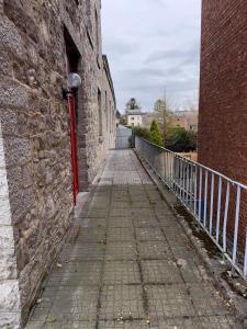 a brick alleyway with a fence next to a brick building at Chez Marloie in Marche-en-Famenne