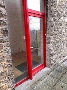 a red door in a stone building with a window at Chez Marloie in Marche-en-Famenne