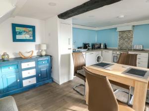 een keuken met blauwe kasten en een houten tafel bij The Mill in Bryngwran
