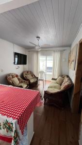 a room with two beds and a table and a tv at Casas de Aluguel da Lulu in Itapema