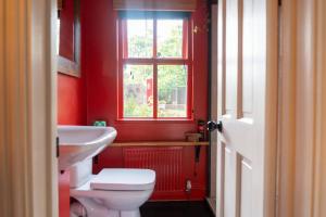 a red bathroom with a toilet and a sink at River Cottage at Old Post Office in Bardon Mill +24 photos