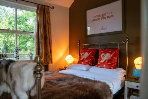 a bedroom with a bed with red pillows and a window at River Cottage at Old Post Office in Bardon Mill