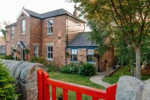 a red fence in front of a brick house at River Cottage at Old Post Office in Bardon Mill