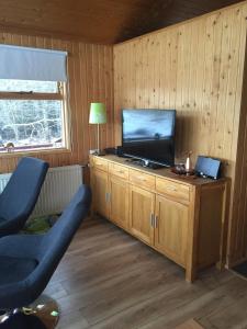 a living room with a television on a wooden cabinet at A cosy 2 bedroom cabin with an amazing view in Borgarnes