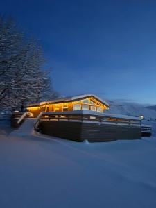 a building in the snow with lights on at A cosy 2 bedroom cabin with an amazing view in Borgarnes