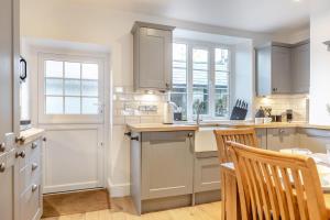 una cucina con mobili bianchi, tavolo e sedie di 2 Bed in Sticklepath oc-l33312 a Sticklepath