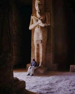 een man die voor een standbeeld van een vrouw zit bij Hllol Hotel Abu Simbel in Abu Simbel