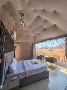 a bedroom with a bed and a large window at RUM ARIZONA lUXURY CAMP in Wadi Rum