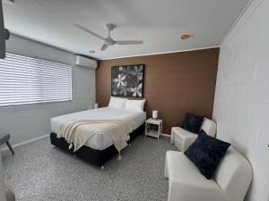 a bedroom with a bed and a couch and a chair at Large Earthy toned Apartment in Ross River