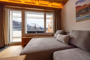 een woonkamer met een bank en een groot raam bij NEW Engadine Alpine Apartment - Pool & Sauna in St. Moritz