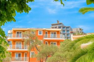 an orange building with white balconies and trees at Better place in Bečići
