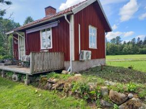 a small red house with a porch and a deck at Stuga Sandhem in Sandhem