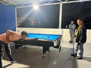 due uomini in piedi attorno a un tavolo da biliardo con di Mi lugar de descanso a Moca Altre 8 foto