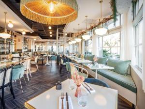 a restaurant with tables and chairs and windows at Mercure La Roche Sur Yon in La Roche-sur-Yon