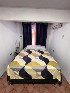 a bedroom with a black and yellow quilt on a bed at Casa Girasol PZ in San Isidro de El General
