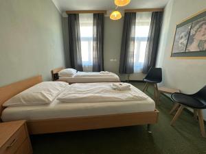 a room with two beds and a chair in it at Mariazellerhof Suite 016 in Sankt Pölten