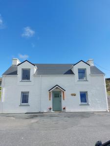 een wit huis met een groene deur bij Costa Glebe in Dungloe