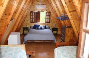 een slaapkamer met een bed in een blokhut bij Alpinasmaquen in Puerto Quequén