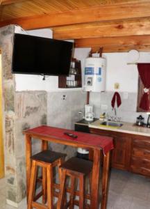 een keuken met een tafel met twee krukken en een tv bij Alpinasmaquen in Puerto Quequén
