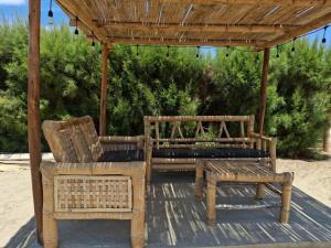 a patio with a bench and a chair and a pergola at Bungalows de Chotos in Los Órganos