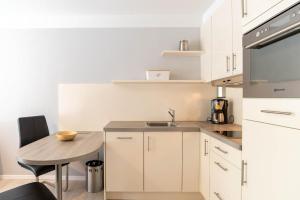 una cucina con mobili bianchi e un tavolino di Untenlinks-Kiel a Schilksee