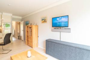 un soggiorno con un divano e una TV a parete di Untenlinks-Kiel a Schilksee Altre 9 foto