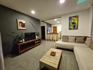 een woonkamer met een bank en een tv bij Maison CATU in Itacaré