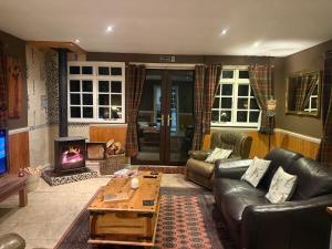 a living room with a leather couch and a fireplace at Cuckoo Cabin, Tyn Y Cwm in Scyborycoed