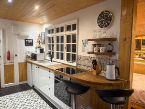 a kitchen with white cabinets and a counter with stools at Cuckoo Cabin, Tyn Y Cwm in Scyborycoed