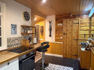 a kitchen with wooden walls and a counter with a stool at Cuckoo Cabin, Tyn Y Cwm in Scyborycoed