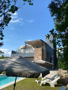 a house with a pool and an umbrella and chairs at Altos del Oeste in Villa Carlos Paz