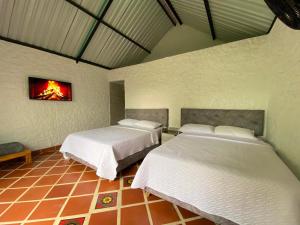two beds in a room with a fire painting on the wall at Cabañas Villa del Prado in Gigante