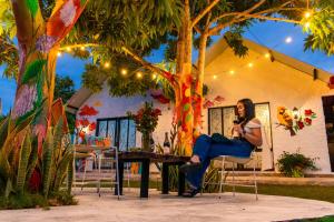 a woman sitting at a table talking on a cell phone at Cabañas Villa del Prado in Gigante