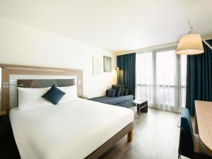 a hotel room with a white bed and a blue couch at Novotel Senart Golf De Greenparc in Saint-Pierre-du-Perray +170 photos