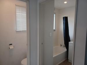 a bathroom with a tub and a toilet and a sink at Cosy Cottage in Ruakaka +25 photos