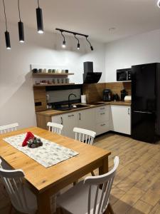 a kitchen with a wooden table and a black refrigerator at Rusiński Raj - Domki in Bukowina Tatrzańska