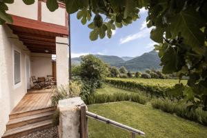 Ein Haus mit einer Holzveranda und Blick auf einen Weinberg in der Unterkunft Smart Suites Kaltern - Apartments am Kalterer See in Kaltern