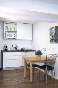 a kitchen with white cabinets and a wooden table and chairs at Grünes Studio in Hameln