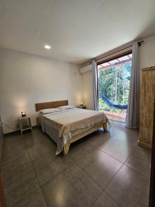 een slaapkamer met een bed en een groot raam bij Maison CATU in Itacaré +31 foto's