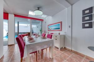 a dining room with a white table and red chairs at Villa Mariña- Heated pool in Playa Blanca